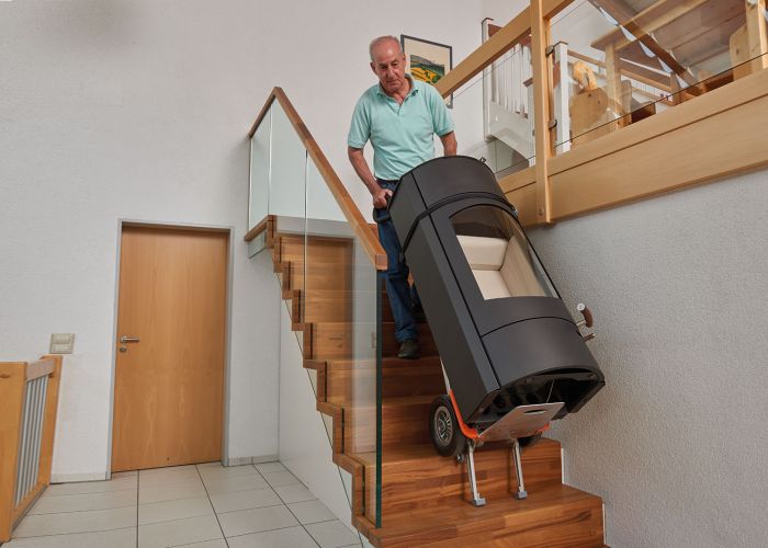 The picture shows the use of the CargoMaster stair climber with a special holder for round goods. It shows how a round oven is transported up and down stairs.